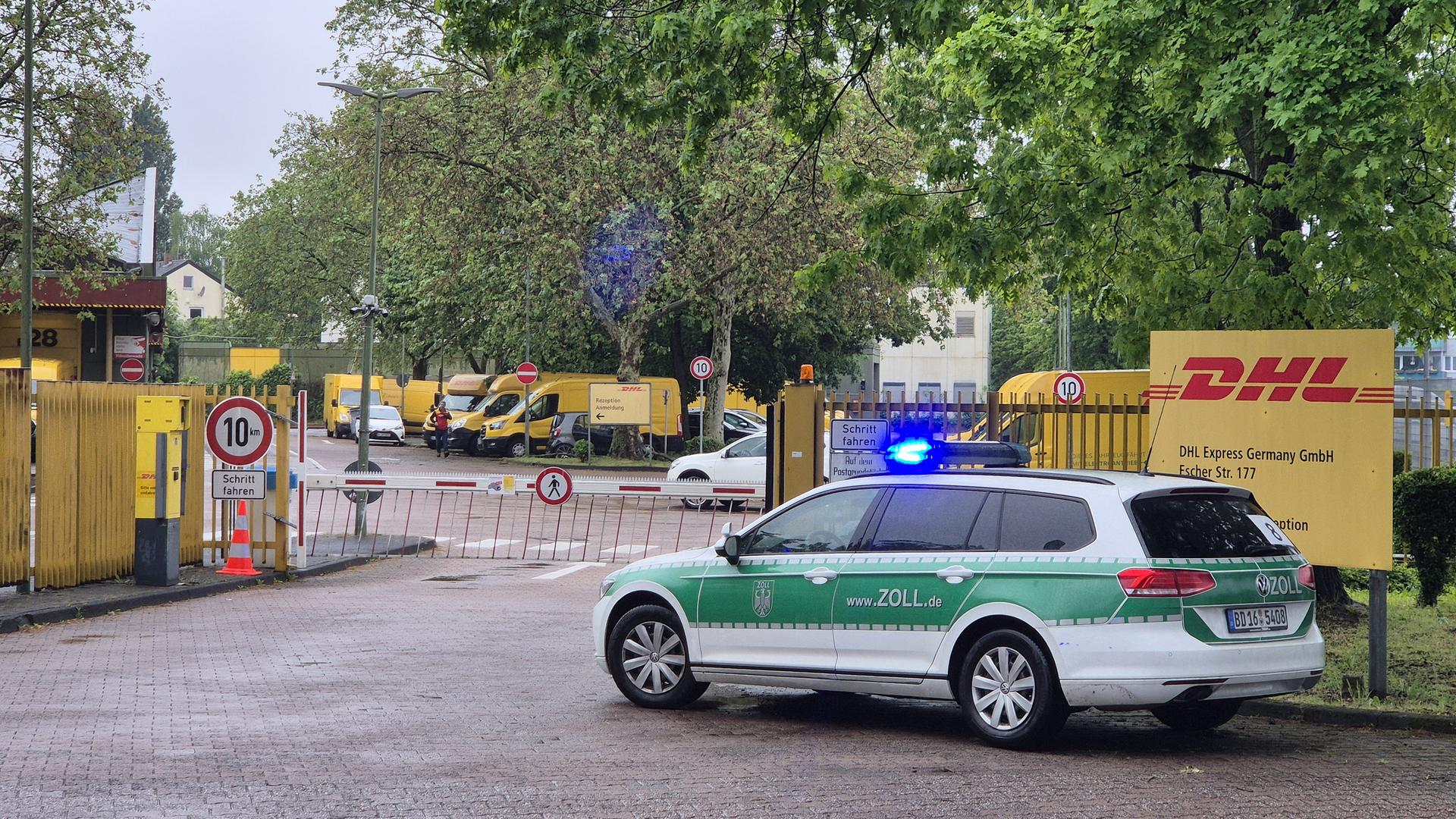 Ein Fahrzeug des Zolls vor dem Tor eines Paketdienstes 