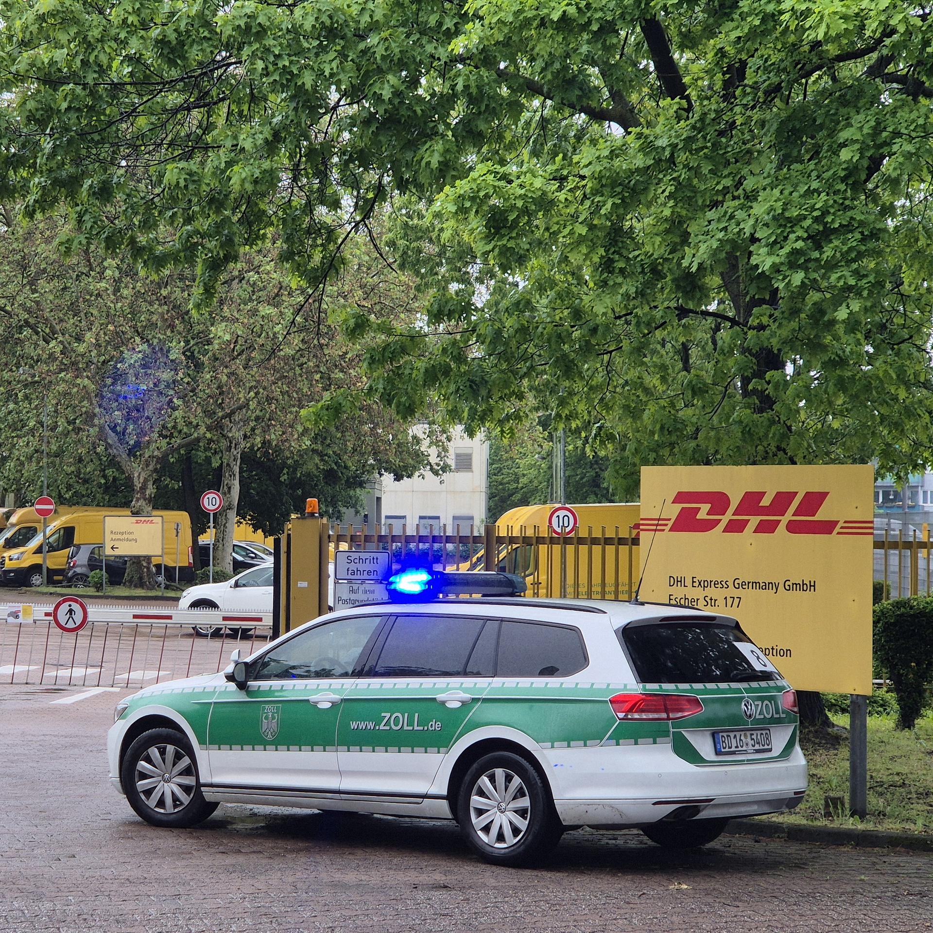 Ein Fahrzeug des Zoll parkt vor dem Tor eines Paketdienstes. 