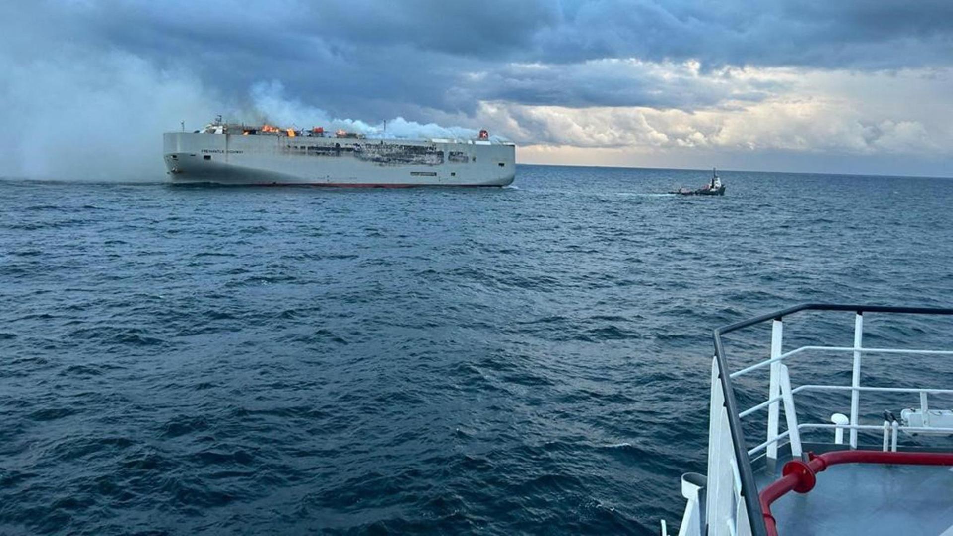 Das Foto zeigt einen Auto-Frachter im Meer vor der niederländischen Küste. Das Schiff brennt, es gibt eine große Rauch-Wolke.