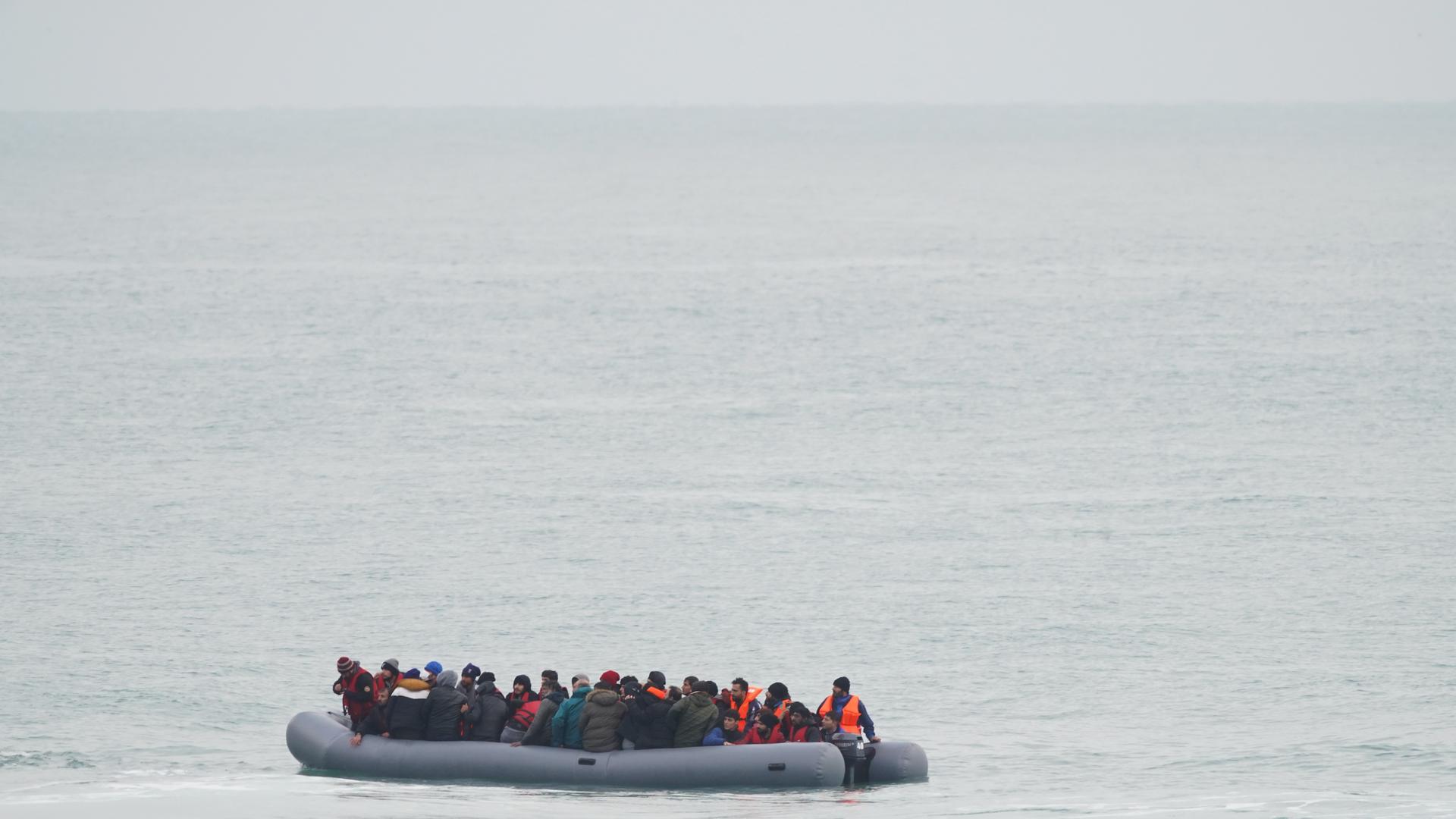 Zu sehen ist eine eine Gruppe von Menschen in einem Schlauchboot auf dem Ärmelkanal bei ruhiger See.