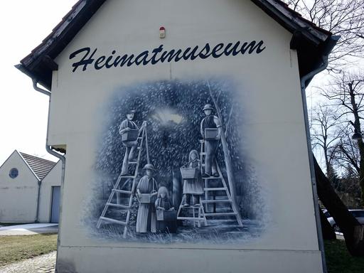 Ein Wandbild an einem Haus zeigt Menschen bei der Apfelernte.