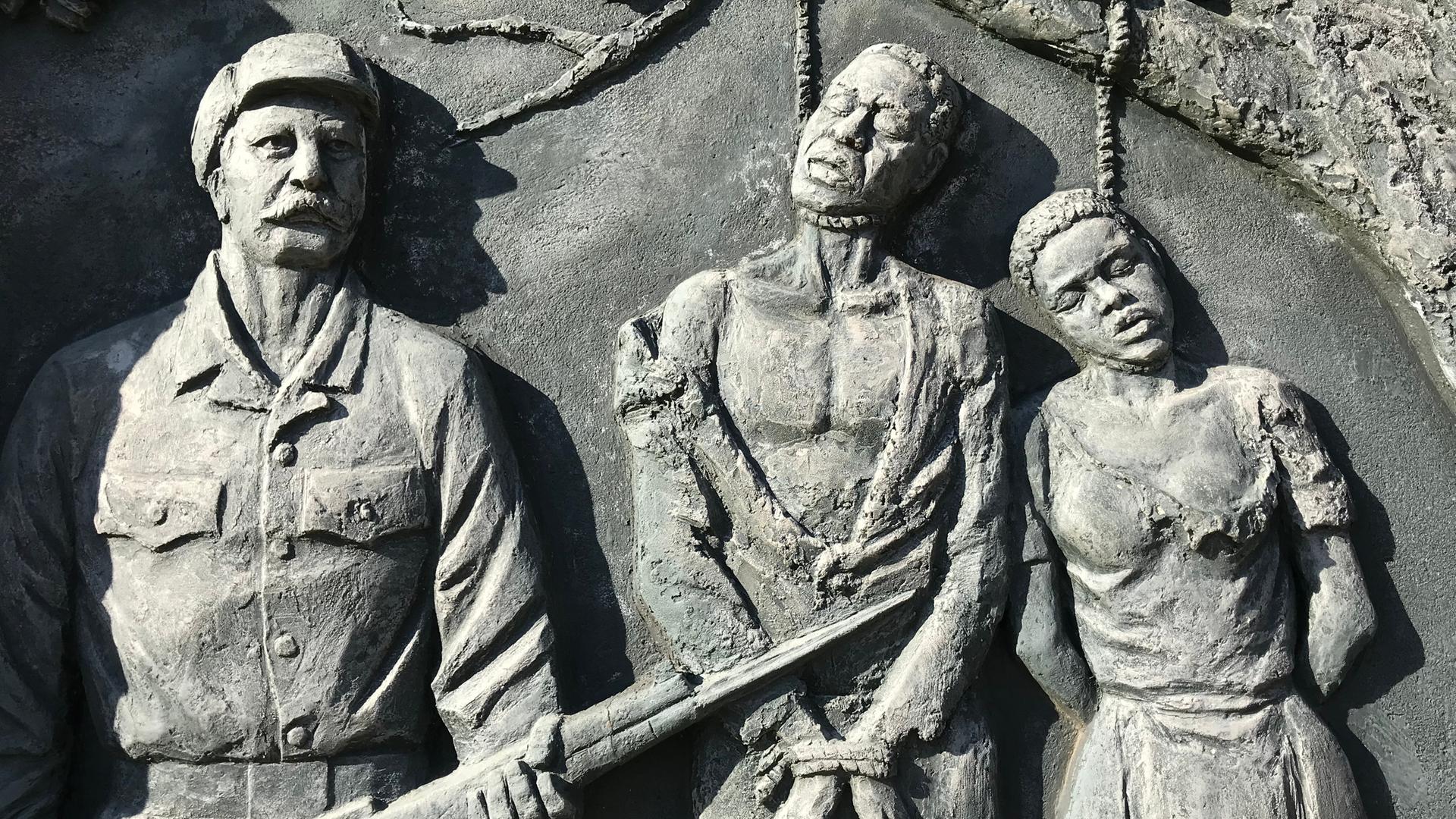 Ein Denkmal zur Erinnerung an den von deutschen Kolonialtruppen begangenen Völkermord an den Herero und Nama zeigt Gehängte neben einem schnauzbärtigen Soldaten.
