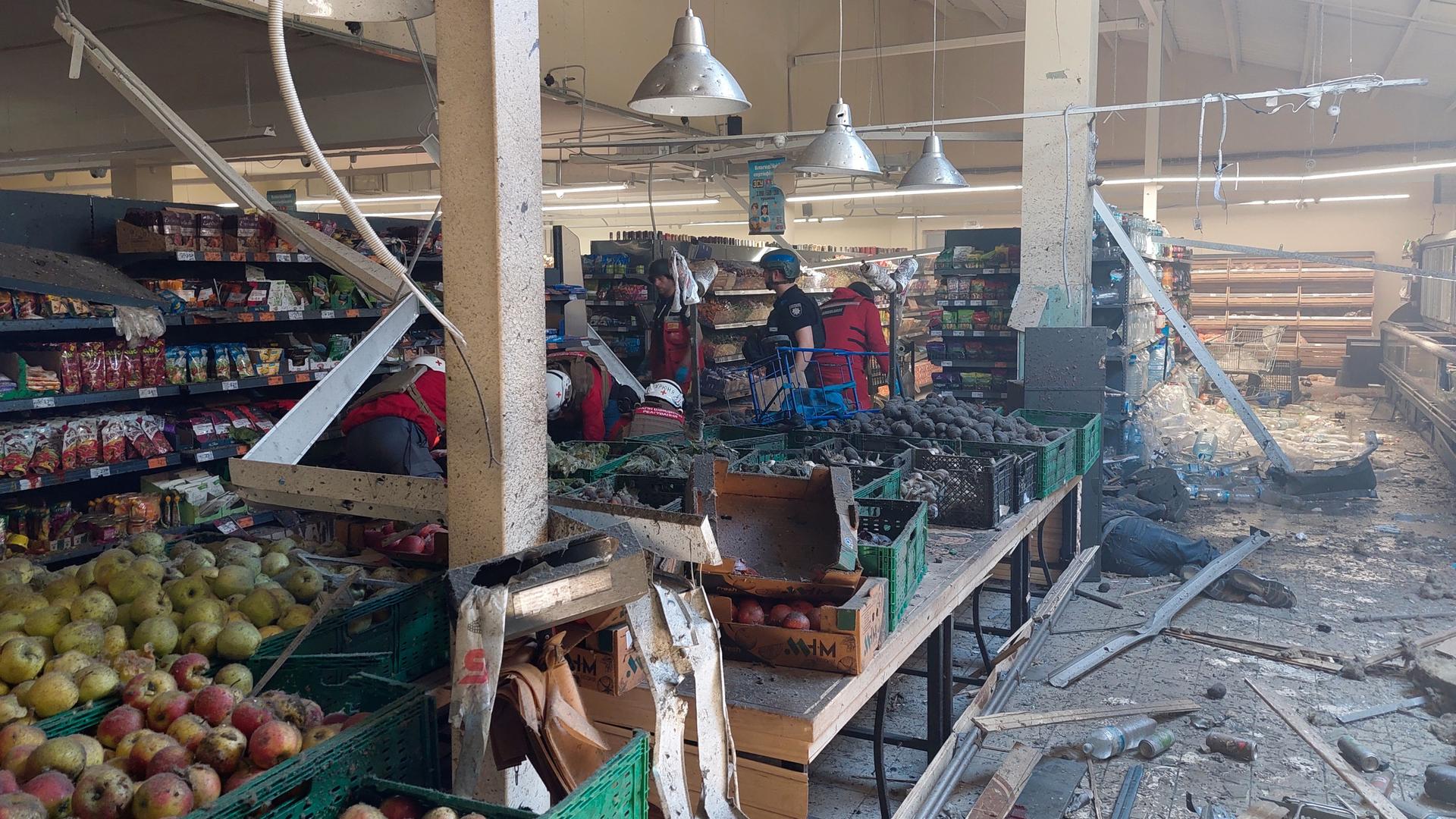 Blick in de schwer beschädigten und verstaubten Laden, in dem noch Obst und andere Güter in den Regalen liegen.