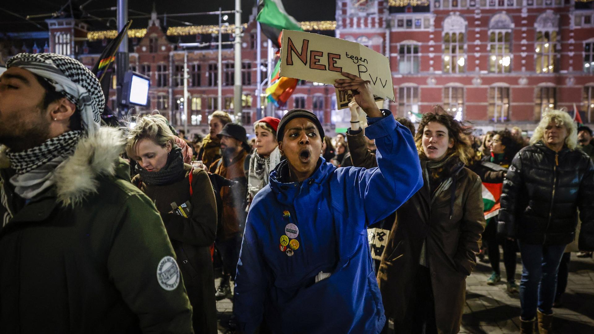 Mehrere Menschen protestierten in Amsterdam gegen den Wahlsieg des rechtsextremen Politikers Geert Wilders. Eine Frau hält ein Schild mit der Aufschrift "Nee PVV" in die Höhe. Mehrere Menschen protestierten in Amsterdam gegen den Wahlsieg des rechtsextremen Politikers Geert Wilders. Eine Frau hält ein Schild mit der Aufschrift "Nee PVV" in die Höhe.