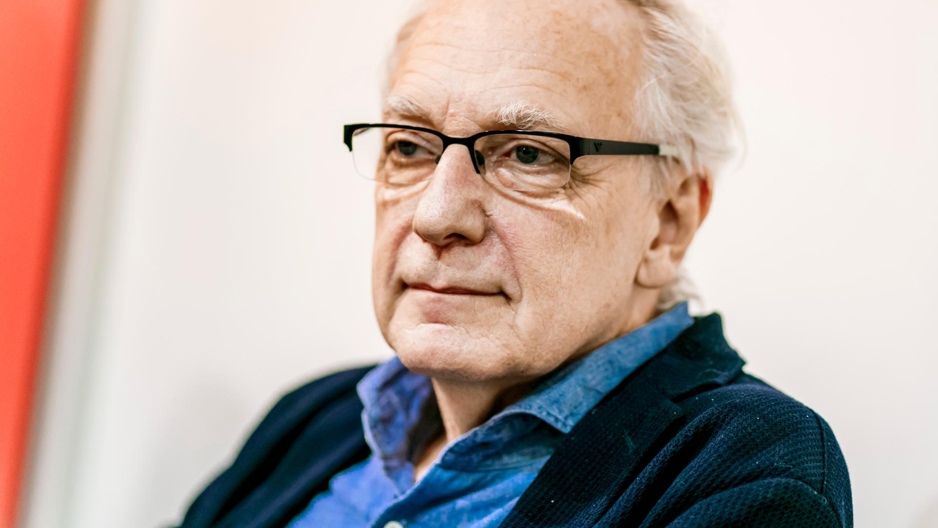 Porträt von Claus Leggewie. Ein älterer Mann mit weißem Haar und eckiger Brille.