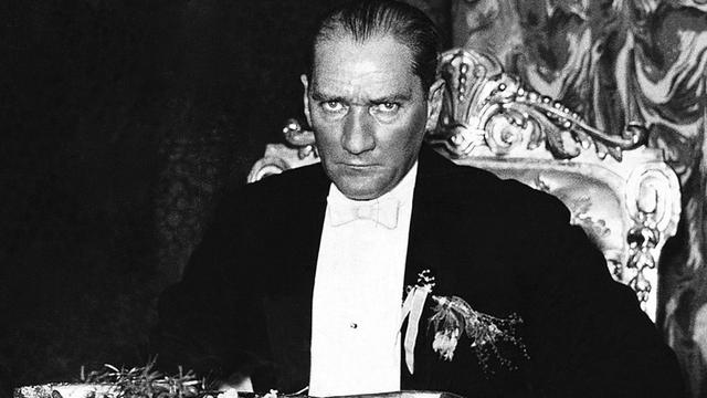 Mustafa Kemal Atatürk sitzt an einem Tisch und blickt ernst in die Kamera Mustafa Kemal Atatürk sitzt an einem Tisch und blickt ernst in die Kamera