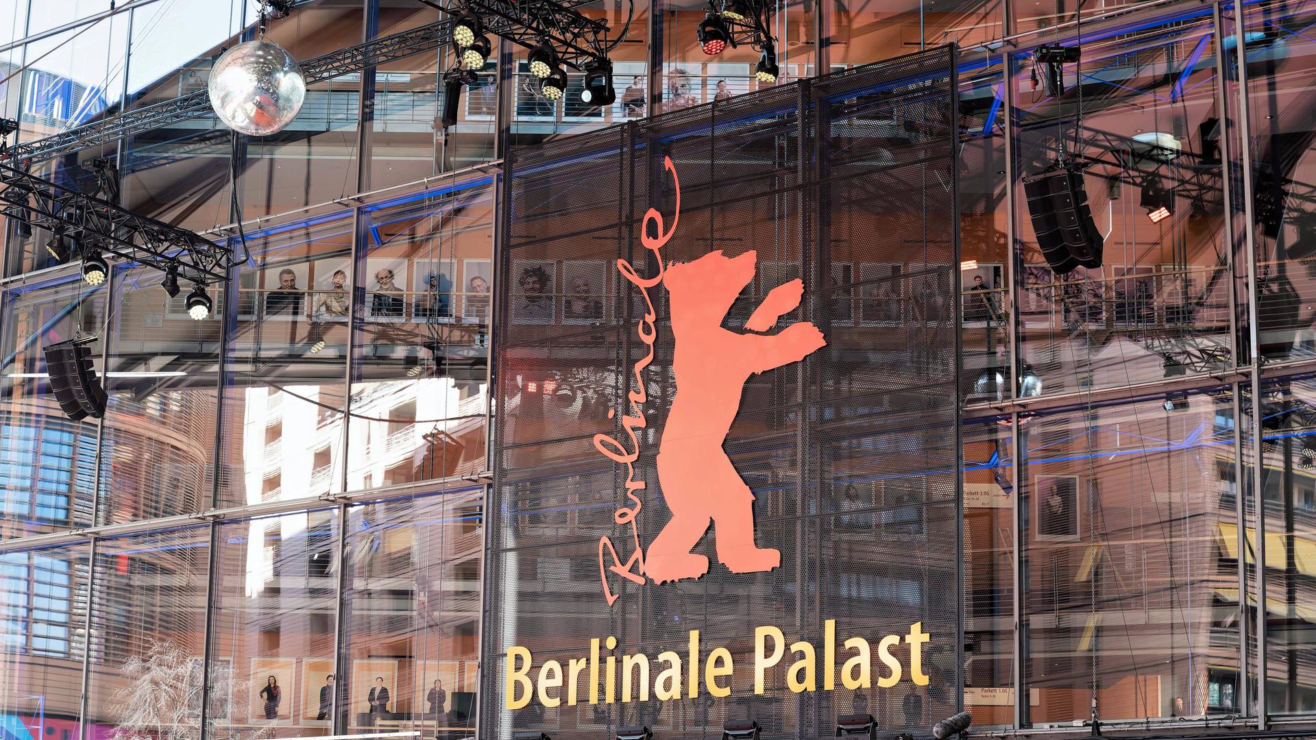 Auf einem Gebäude mit Glasfassade steht auf einem Plakat die Aufschrift Berlinale, daneben ein roter Bär. 