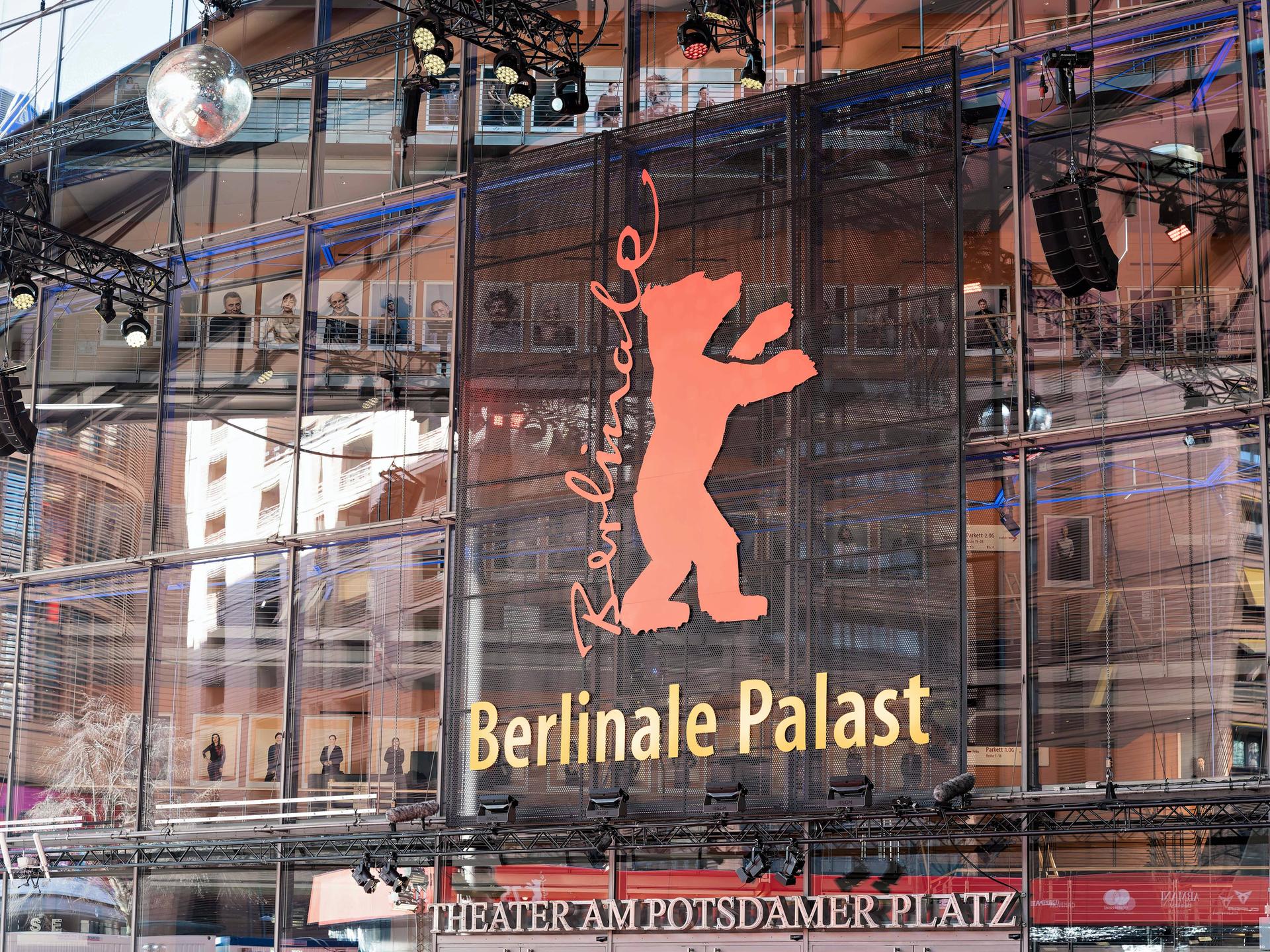 Auf einem Gebäude mit Glasfassade steht auf einem Plakat die Aufschrift Berlinale, daneben ein roter Bär. 