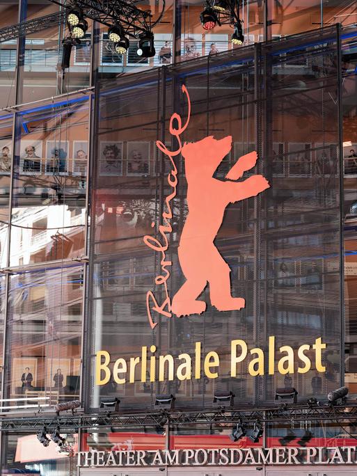 Auf einem Gebäude mit Glasfassade steht auf einem Plakat die Aufschrift Berlinale, daneben ein roter Bär. 