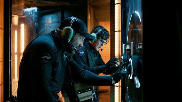 Filmstill aus der Serie "Kaleidoskop". Zwei Männer vor einem Tresor, Jai Courtney als Bob Goodwin und Peter Mark Kendall als Stan Loomis in der Episode "White", 2022.