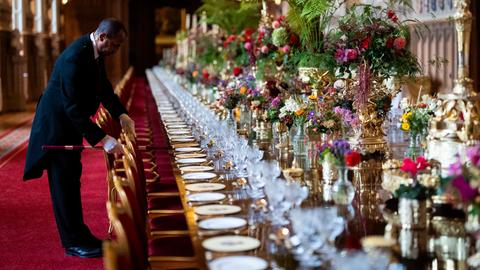 Die Stühle am elegant gedecktem Banketttisch in der St. Georges Hall werden von einem Angestellten im richtigen Abstand zueinander aufgestellt im Vorfeld eines Staatsbanketts im Windsor Castle in England. Die Stühle am elegant gedecktem Banketttisch in der St. Georges Hall werden von einem Angestellten im richtigen Abstand zueinander aufgestellt im Vorfeld eines Staatsbanketts im Windsor Castle in England.