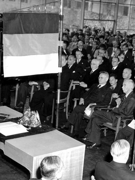 Unter einer schwarz-rot-goldenen Standarte liegt am 23.5.1949 das Grundgesetz der Bundesrepublik Deutschland auf einem Tisch im Sitzungssaal des Parlamentarischen Rates in Bonn. Das Gremium war an diesem Tag um 16.00 Uhr zu seiner letzten Sitzung zusammengetroffen. Während der Feierstunde unterzeichneten 68 Abgeordnete einschlieÃlich der Westberliner Vertreter das Grundgesetz der Bundesrepublik Deutschland. Der kommunistische Abgeordnete Heinz Renner und der KPD-Vorsitzende Max Reimann lehnten die Unterzeichnung ab. Zwei Wochen zuvor, am 8. Mai 1949, war das Grundgesetz vom Plenum des Parlamentarischen Rates mit 53 gegen zwölf Stimmen endgültig angenommen worden.