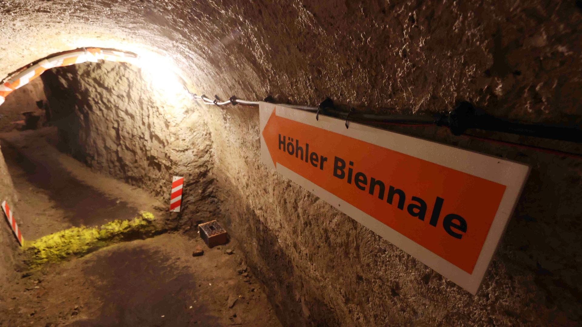 Ein Hinweisschild zeigt zum Eingang der Höhlerbiennale in einem Höhler unter der Stadt. Ein Hinweisschild zeigt zum Eingang der Höhlerbiennale in einem Höhler unter der Stadt.