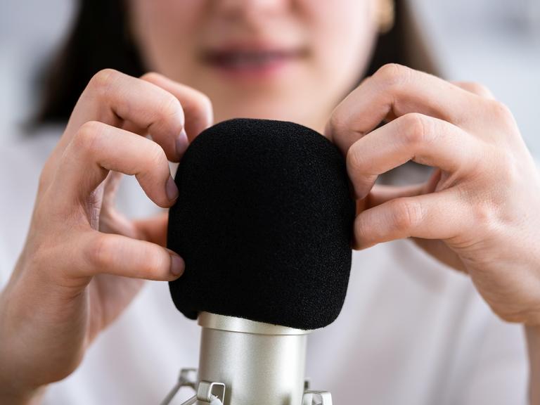 Eine Frau kratzt mit ihren Fingern an einem Mikrofon.