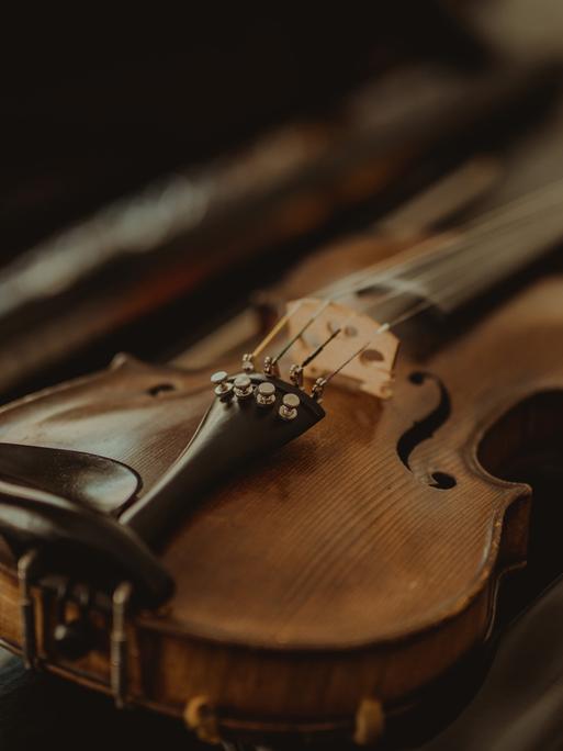 Wiederentdeckte Instrumente werden  zu neuem musikalischen Leben erweckt. Zu sehen: Eine kleine Geige liegt auf einem Tisch, dahinter der geöffbete Geigenkasten.