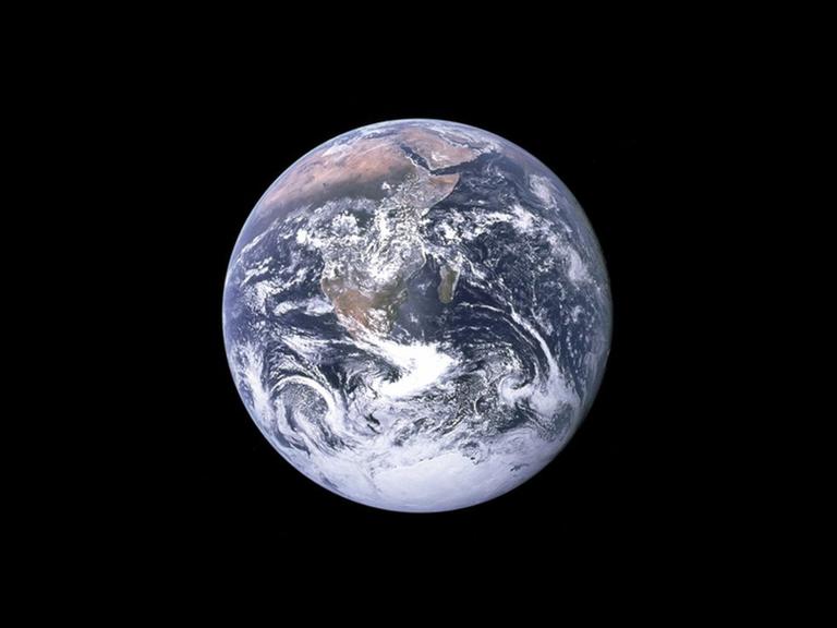 Die sonnenbeleuchtete Erde ist in Großaufnahme im sonst schwarzen Weltall zu sehen.