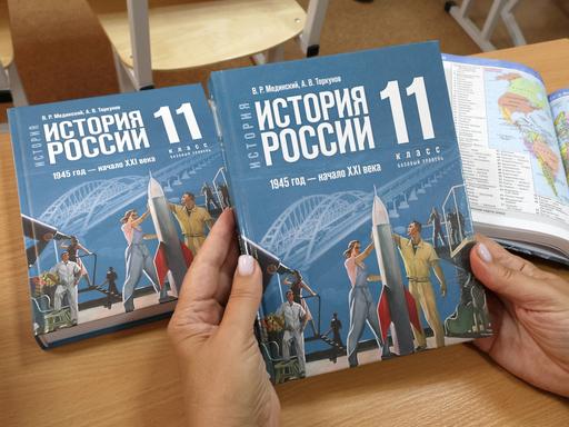 Zwei Hände halten die neue Ausgabe des russischen Geschichtsbuchs für die 10. und 11. Klasse. 