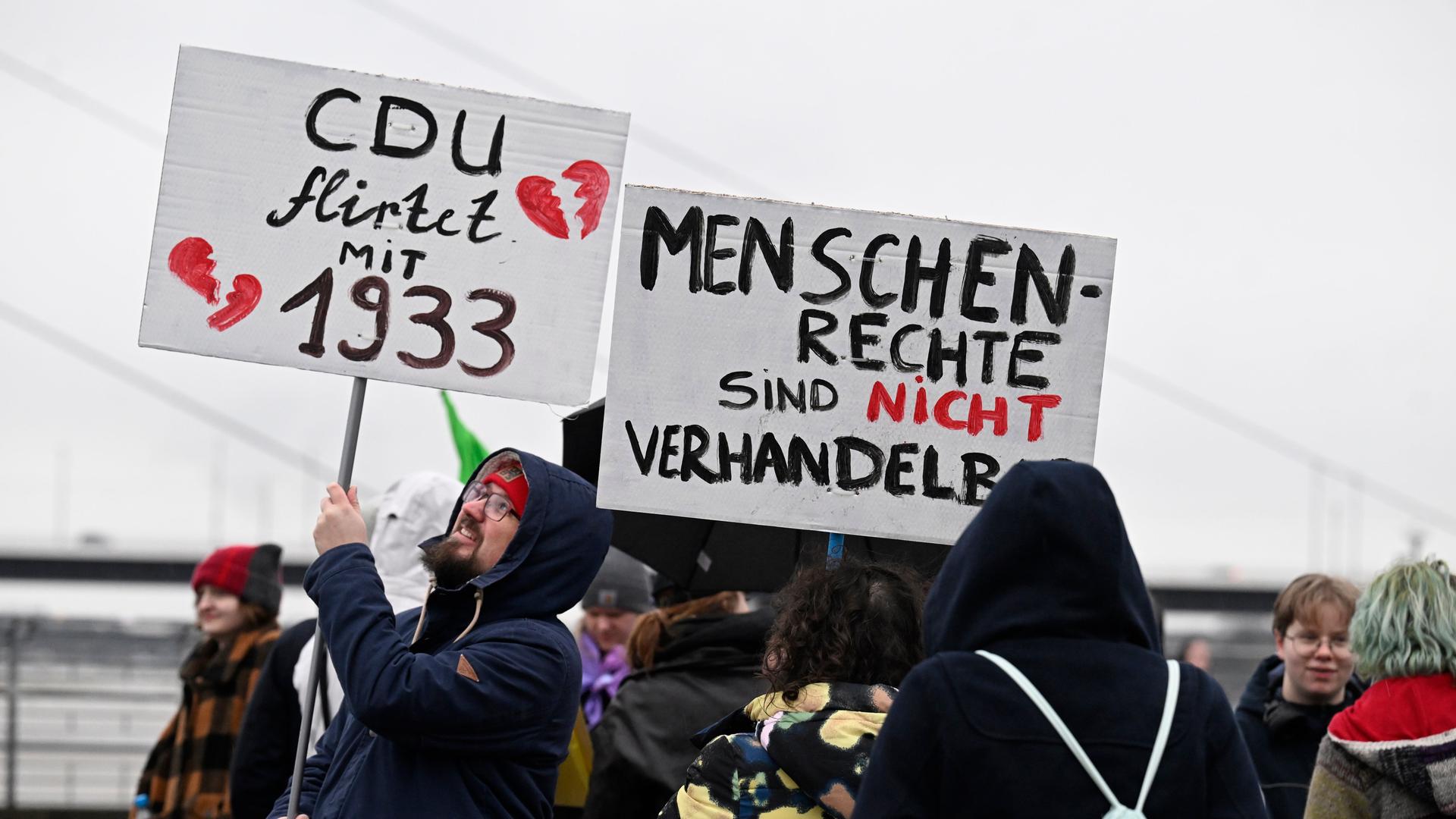 Teilnehmer einer Demonstration in Düsseldorf zur Migrationspolitik halten Schilder mit den Aufschriften "CDU flirtet mit 1933" und "Menschenrechte sind nicht verhandelbar".