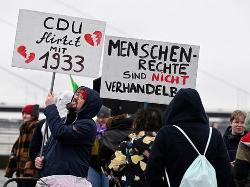 Teilnehmer einer Demonstration in Düsseldorf zur Migrationspolitik halten Schilder mit den Aufschriften "CDU flirtet mit 1933" und "Menschenrechte sind nicht verhandelbar".