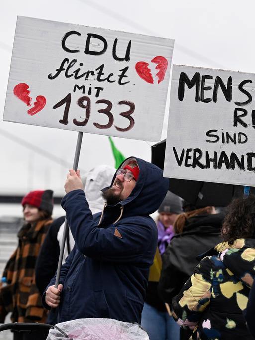 Teilnehmer einer Demonstration in Düsseldorf zur Migrationspolitik halten Schilder mit den Aufschriften "CDU flirtet mit 1933" und "Menschenrechte sind nicht verhandelbar".