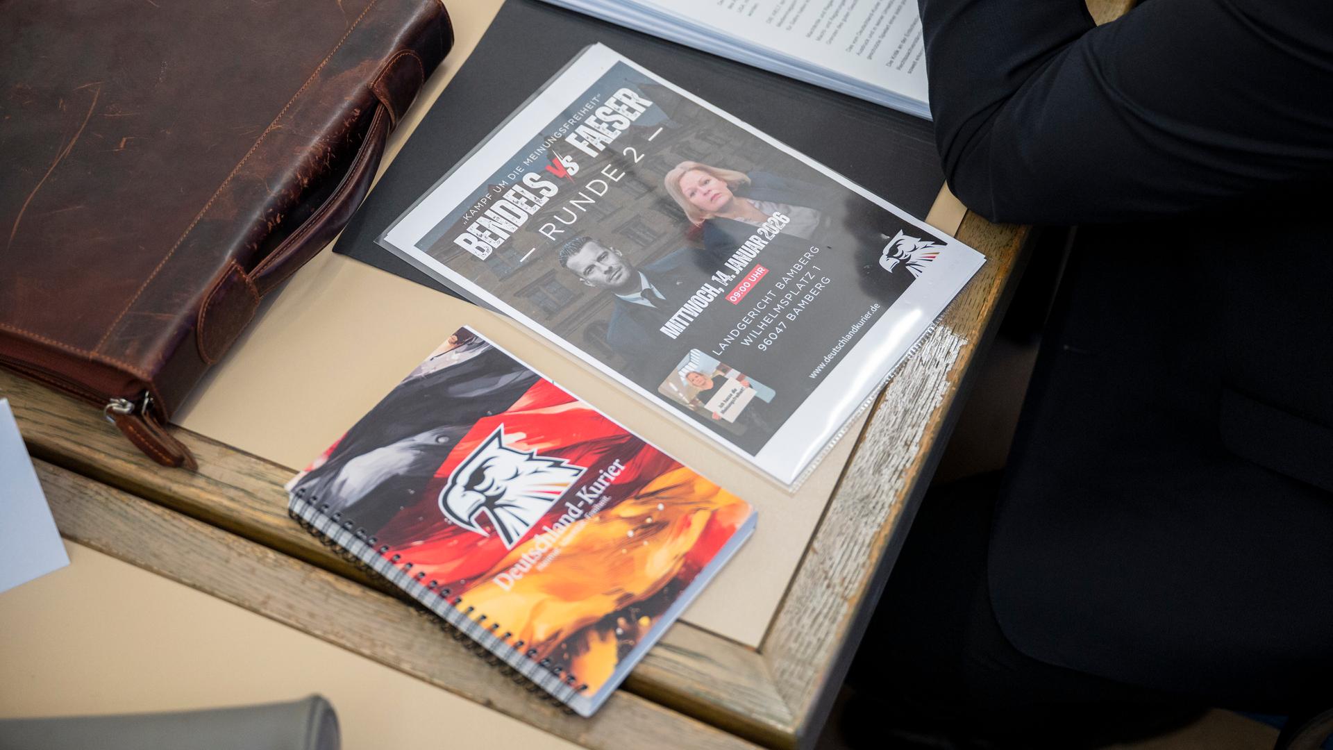 Auf dem Tisch des Angeklagten liegt ein Blatt mit der Aufschrift „Kampf um die Meinungsfreiheit Bendels vs Faeser Runde 2“. 