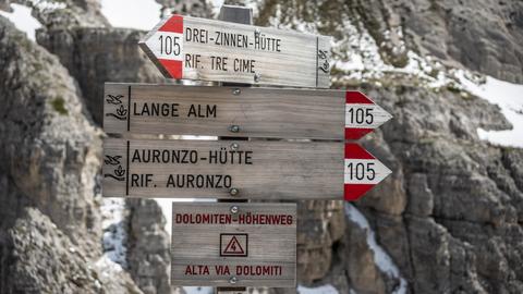 Wegweiser auf einem Wanderweg mit zweisprachiger Beschriftung auf Deutsch und Italienisch.