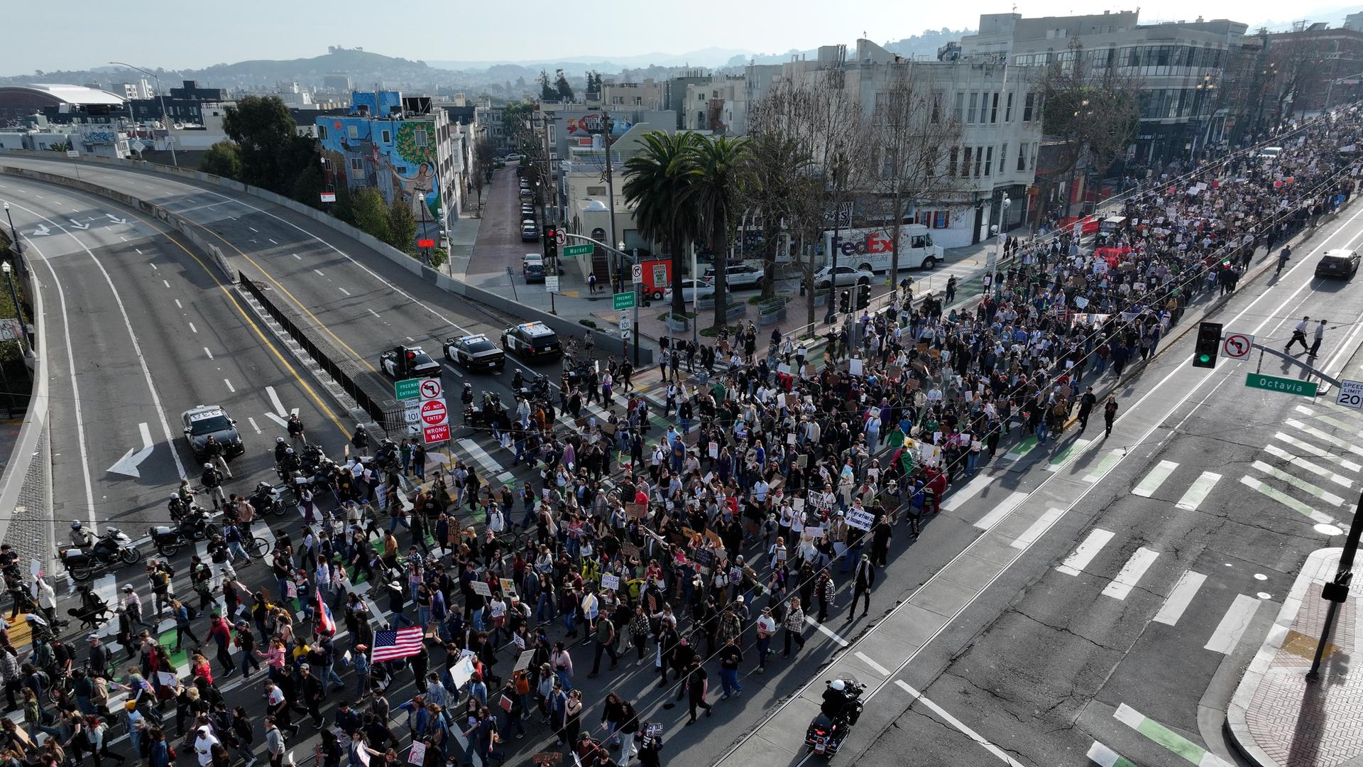 Ein Demonstrationszug mit Fahnen und Bannern zieht durch eine große Hauptverkehrsstraße in San Francisco Ein Demonstrationszug mit Fahnen und Bannern zieht durch eine große Hauptverkehrsstraße in San Francisco