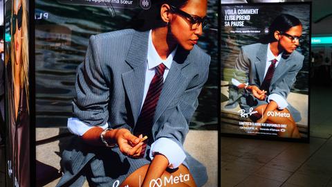 Ein Werbedisplay mit Werbung für die neue Meta-Brille von Ray Ban. Eine Frau mit Anzug und Krawatte trägt die Brille. Ein Werbedisplay mit Werbung für die neue Meta-Brille von Ray Ban. Eine Frau mit Anzug und Krawatte trägt die Brille.