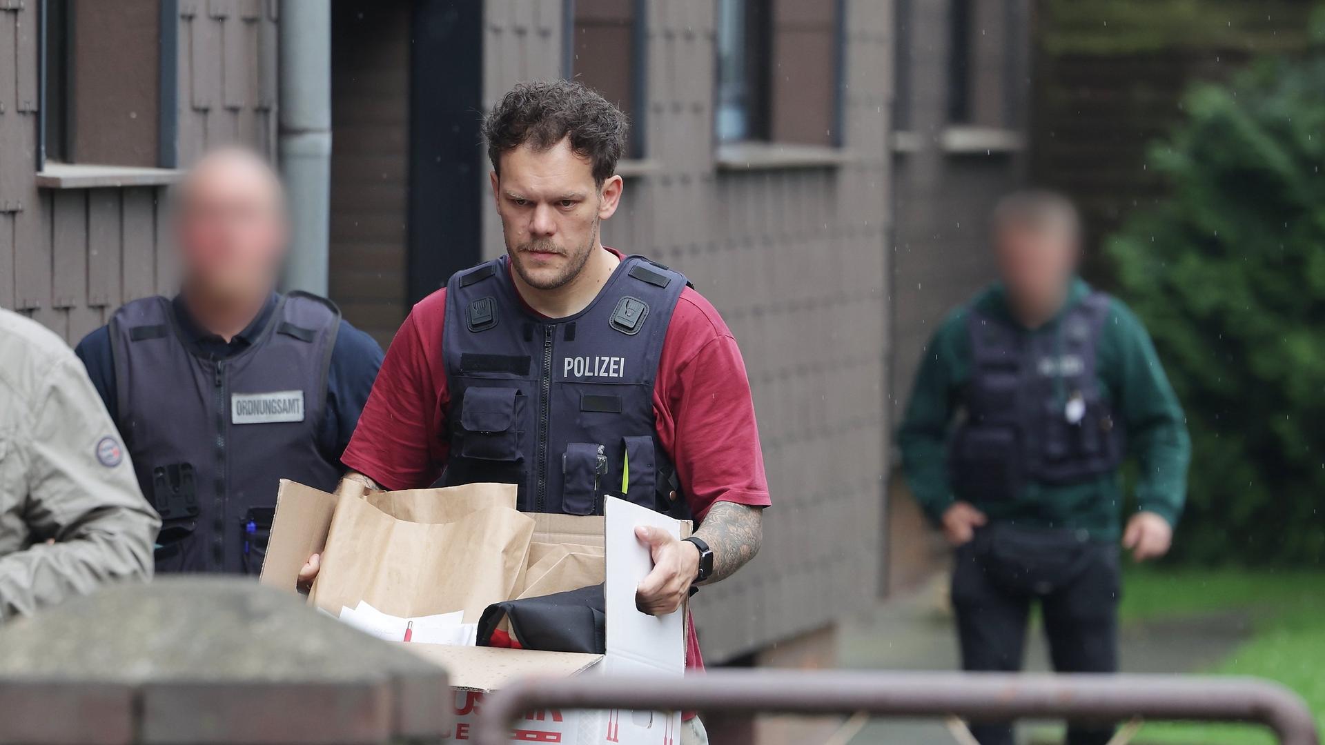 Duisburg: Nach einer Wohnungsdurchsuchung trägt ein Polizist einen Karton mit sichergestellten Gegenständen. Duisburg: Nach einer Wohnungsdurchsuchung trägt ein Polizist einen Karton mit sichergestellten Gegenständen.