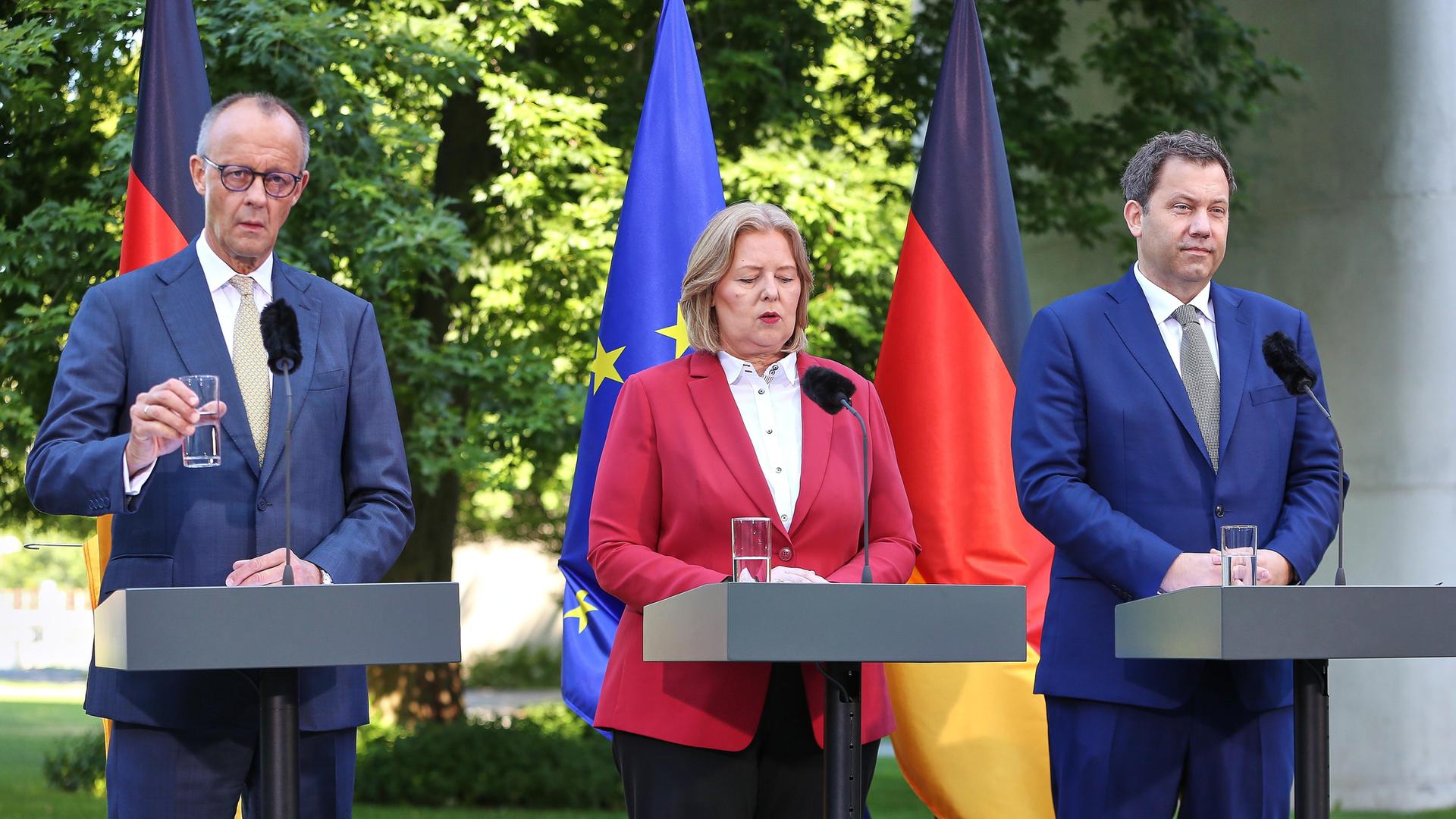 Bundes-Kanzler Friedrich Merz, Arbeits-Ministerin Bärbel Bas und Finanz-Minister Lars Klingbeil stehen vor Rede-Pulten. Sie sprechen vor Journalisten.