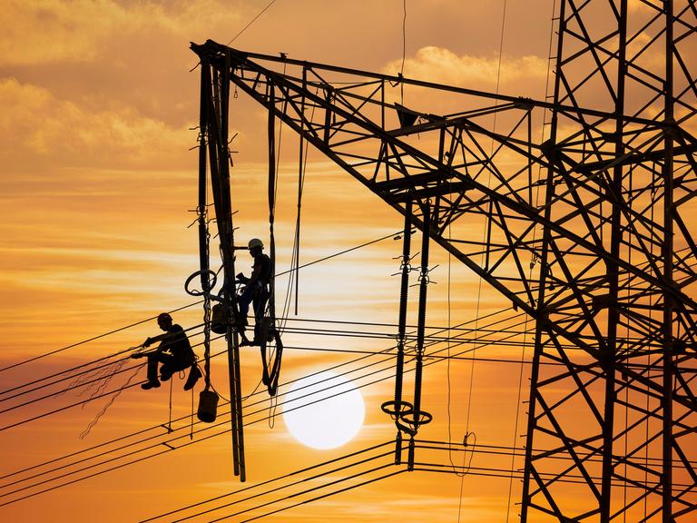 Monteure arbeiten an einem Hochspannungsmast bei Sonnenuntergang in Baden-Württemberg Monteure arbeiten an einem Hochspannungsmast bei Sonnenuntergang in Baden-Württemberg