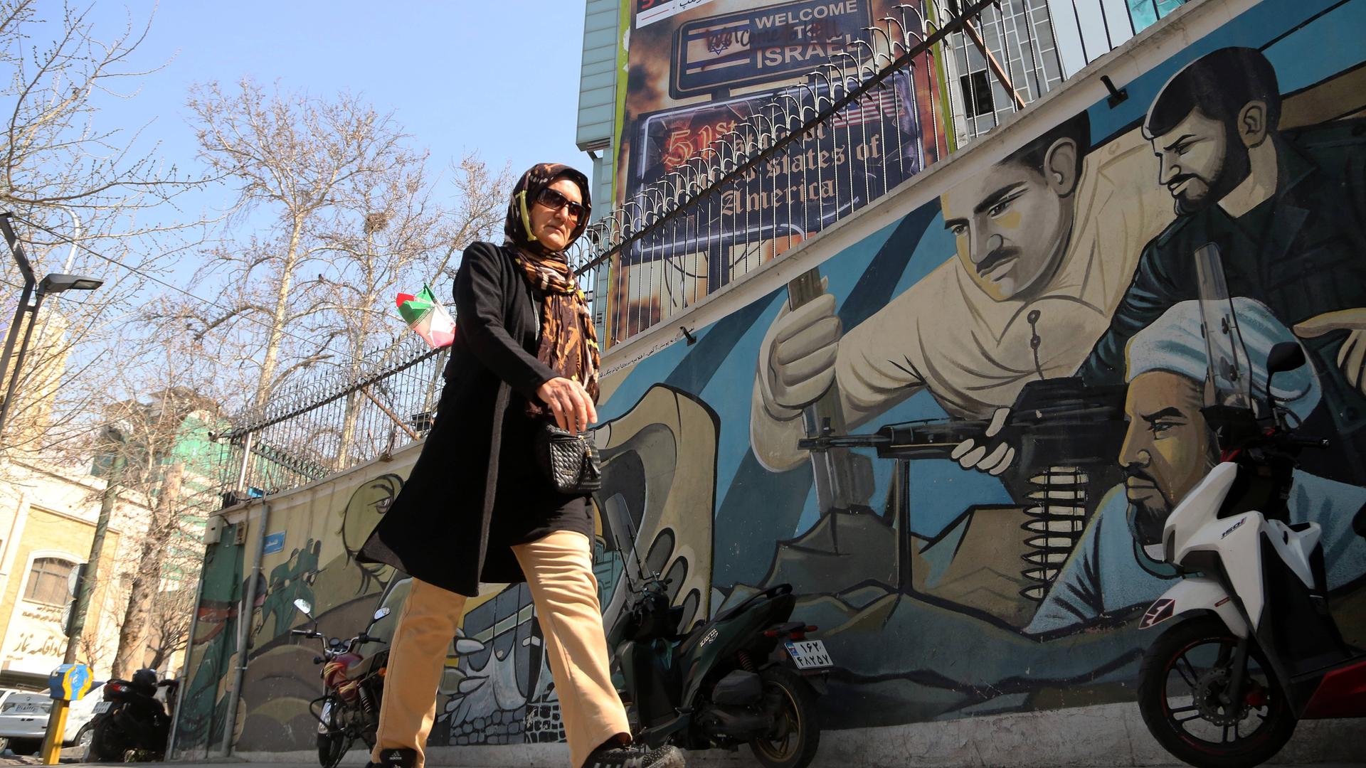 Eine Frau läuft am 25. Februar 2026 in Teheran an anti-israelischer und anti-amerikanischer Propaganda vorbei.