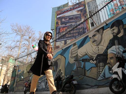 Eine Frau läuft am 25. Februar 2026 in Teheran an anti-israelischer und anti-amerikanischer Propaganda vorbei.