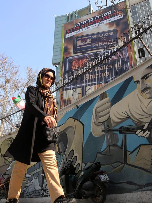 Eine Frau läuft am 25. Februar 2026 in Teheran an anti-israelischer und anti-amerikanischer Propaganda vorbei.