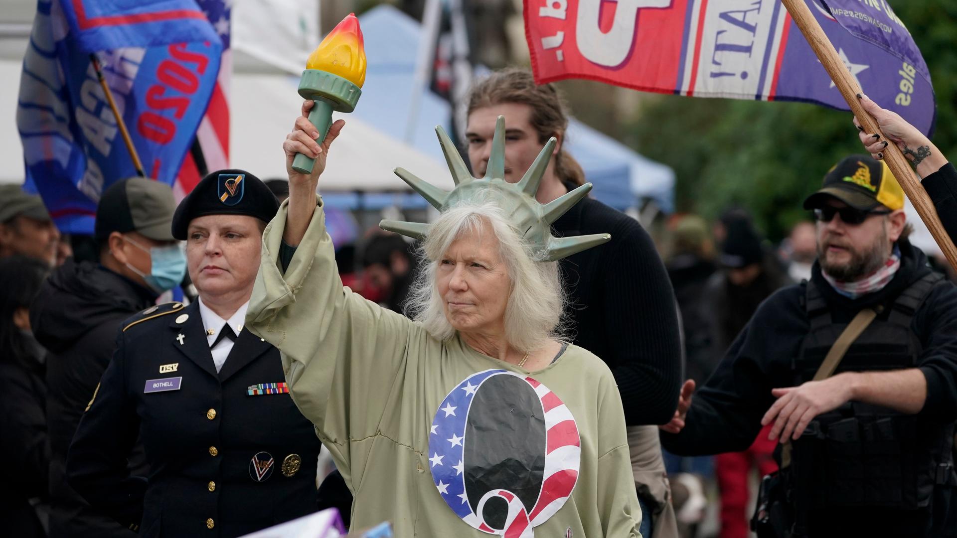 Demonstranten vor dem US-Capitol. Eine Frau hat sich als Freiheitsstatue verkleidet und trägt ein T-Shirt der rechtsextremen  QAnon-Bewegung. 