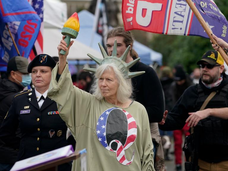 Demonstranten vor dem US-Capitol. Eine Frau hat sich als Freiheitsstatue verkleidet und trägt ein T-Shirt der rechtsextremen  QAnon-Bewegung. 