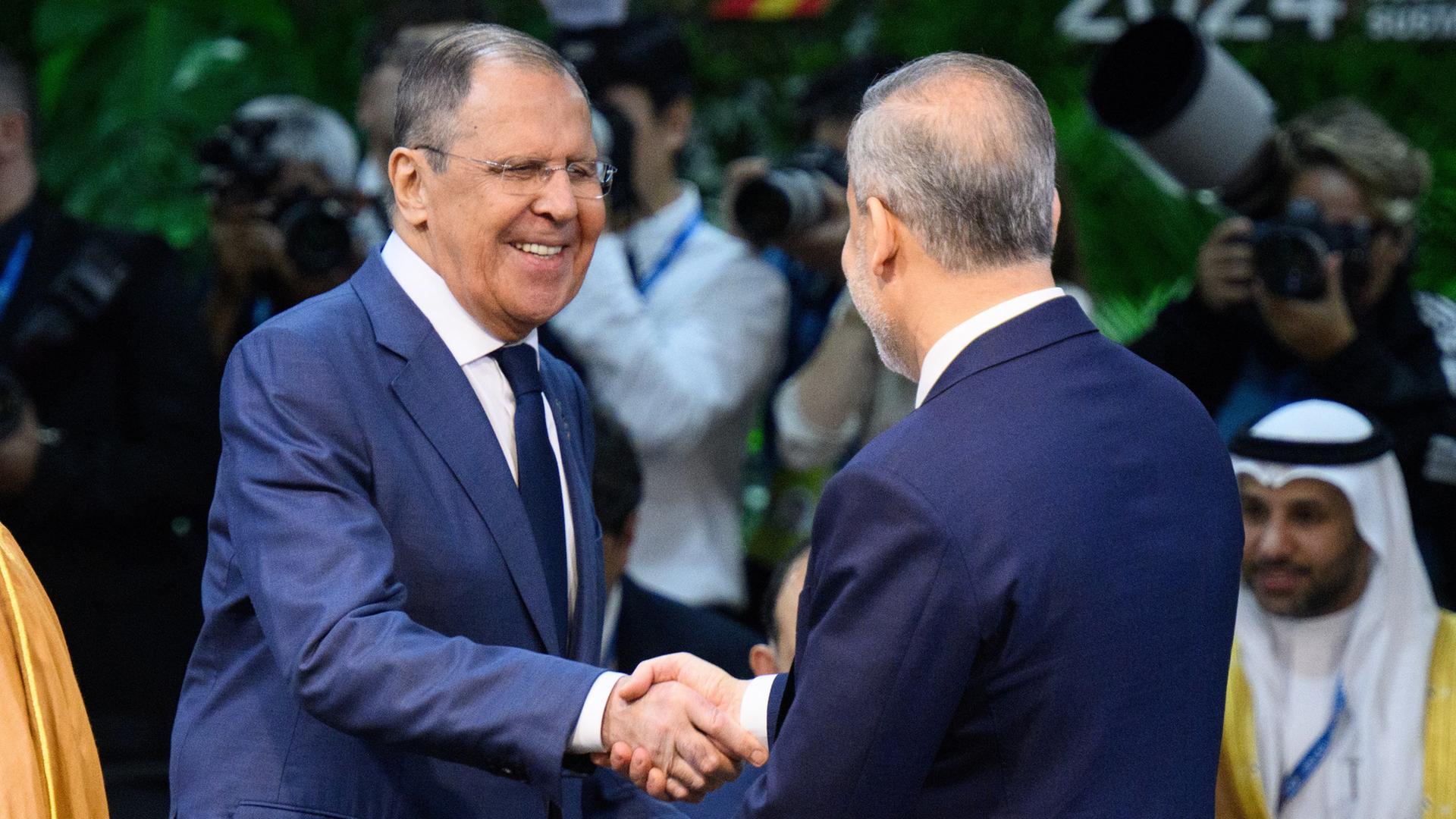 Sergej Lawrow Außenminister von Russland, und Hakan Fidan, Außenminister der Türkei, begrüßen sich zu Beginn der ersten Arbeitssitzung des G20-Außenministertreffens in Rio de Janeiro per Handschlag.