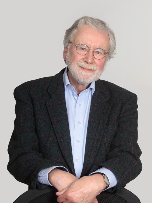 Studioportrait von Dr. Kroener, er trägt einen grauen Anzug, ein hellblaues Hemd und Bart und schaut freundlich in die Kamera