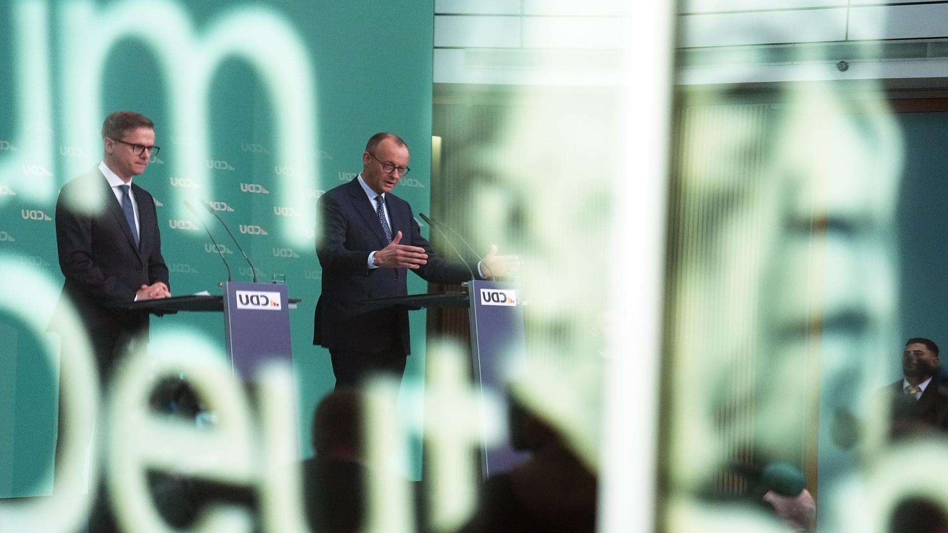 CDU-Chef Friedrich Merz (M) und sein Generalsekretär Carsten Linnemann bei einer Pressekonferenz nach der Sitzung des CDU-Vorstands. Auf der Scheibe im Vordergund ist das Konterfei von Kornad Adenauer zu sehen.