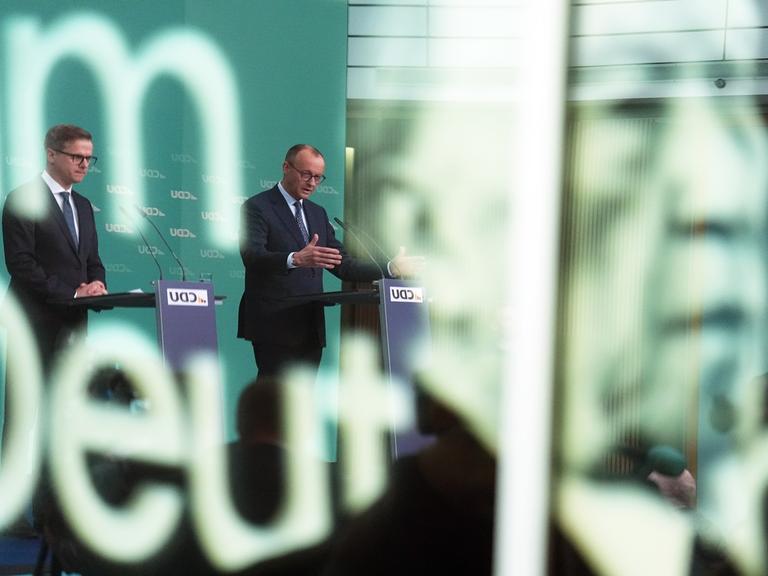 CDU-Chef Friedrich Merz (M) und sein Generalsekretär Carsten Linnemann bei einer Pressekonferenz nach der Sitzung des CDU-Vorstands. Auf der Scheibe im Vordergund ist das Konterfei von Kornad Adenauer zu sehen.