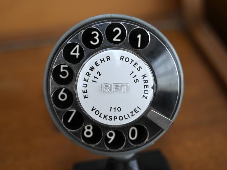 Notrufnummern der Feuerwehr und Polizei aangezeigt auf einer Wählscheibe eines Telefons aus DDR-Zeiten.