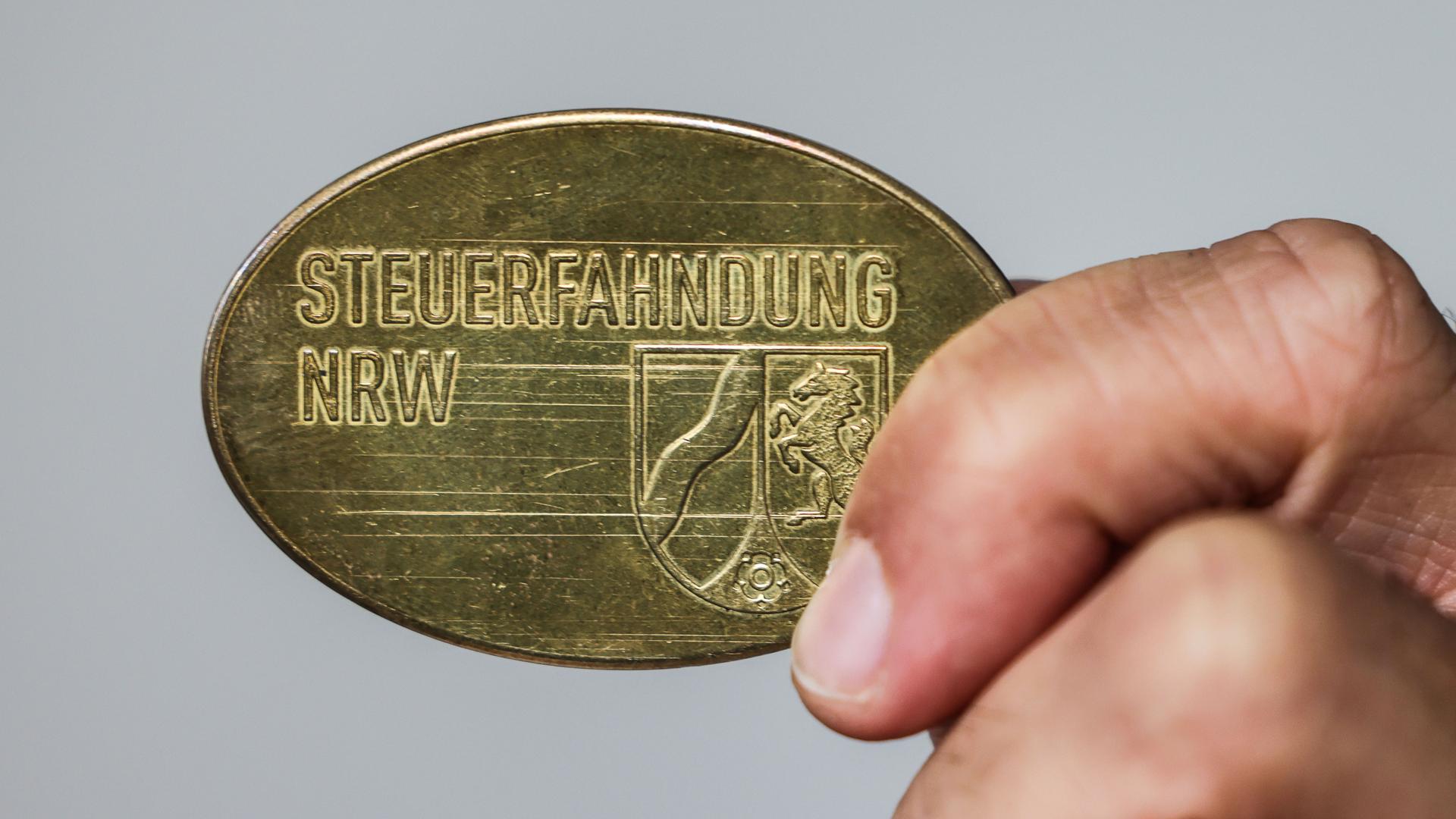 Ein Mitarbeiter im Landesamt zur Bekämpfung der Finanzkriminalität (LBF) zeigt eine Dienstmarke mit der Aufschrift "Steuerfahndung NRW".