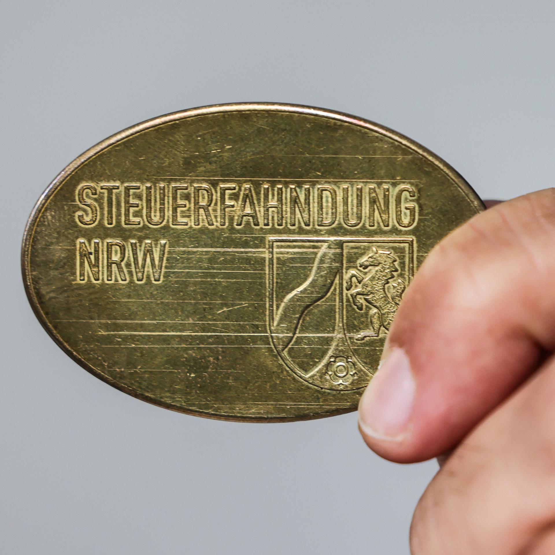 Ein Mitarbeiter im Landesamt zur Bekämpfung der Finanzkriminalität (LBF) zeigt eine Dienstmarke mit der Aufschrift "Steuerfahndung NRW".