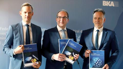 Hendrik Streeck, Alexander Dobrindt und Holger Münch (v.li.) halten Infobroschüren in den Händen bei der Pressekonferenz Bundeslagebilder Organisierte Kriminalität und Rauschgiftkriminalität im Bundeskriminalamt.