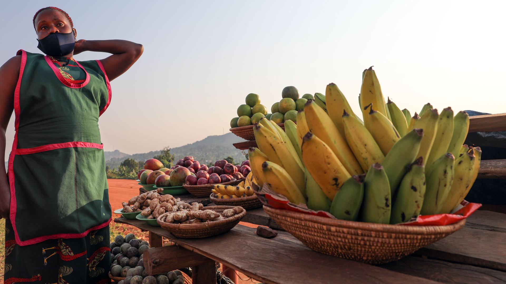 Eine Frau steht an einem Korb mit Obst in Kampala, Uganda.