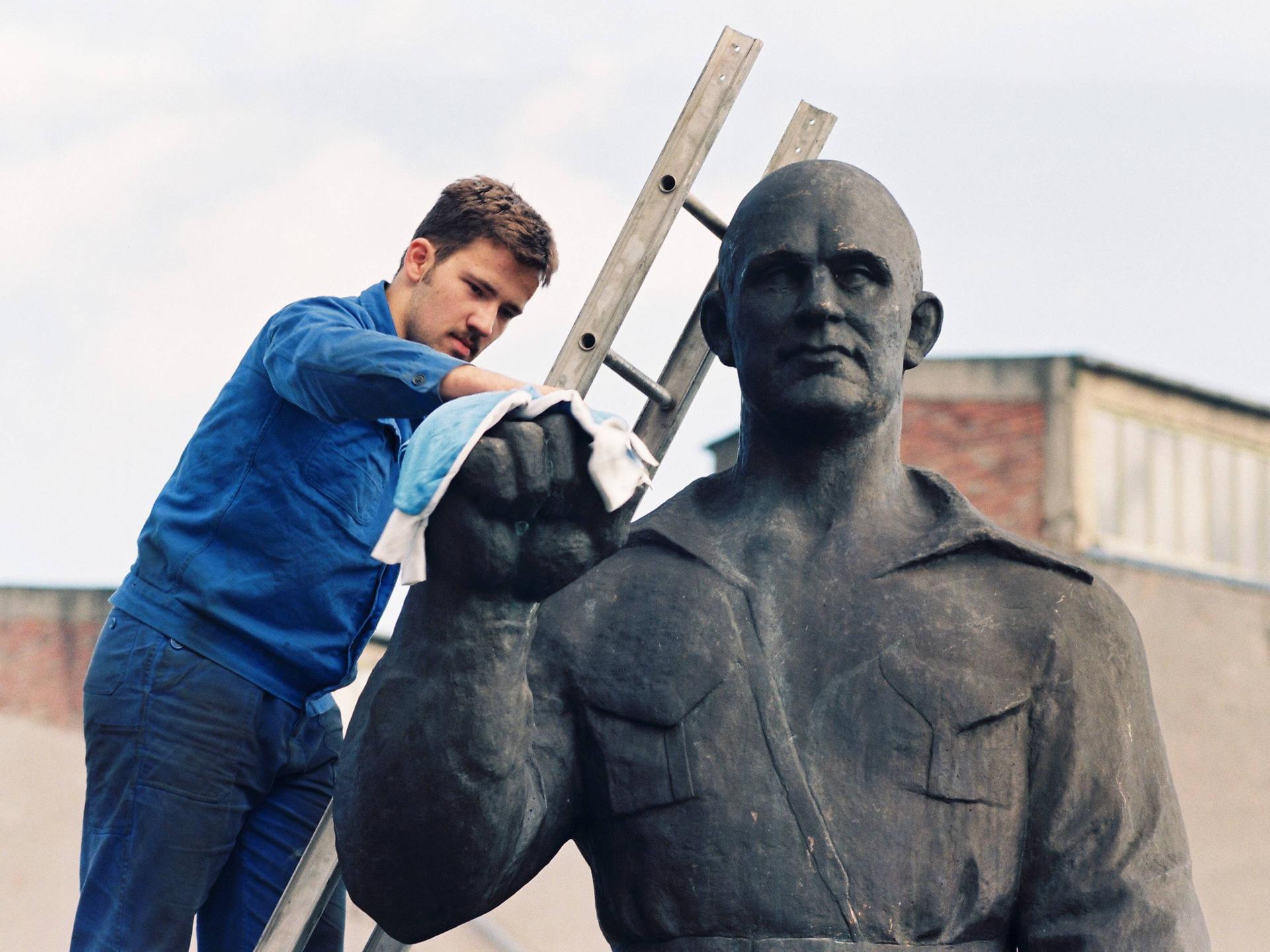 Ein Mann auf einer Leiter putzt eine Büste von Ernst Thälmann im ehemaligen Schwermaschinenbau-Kombinat Sket am 9. September 1994.