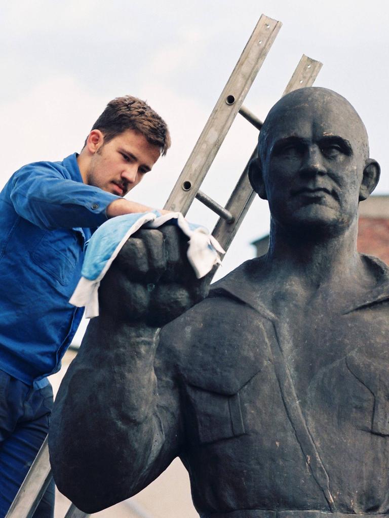 Ein Mann auf einer Leiter putzt eine Büste von Ernst Thälmann im ehemaligen Schwermaschinenbau-Kombinat Sket am 9. September 1994.