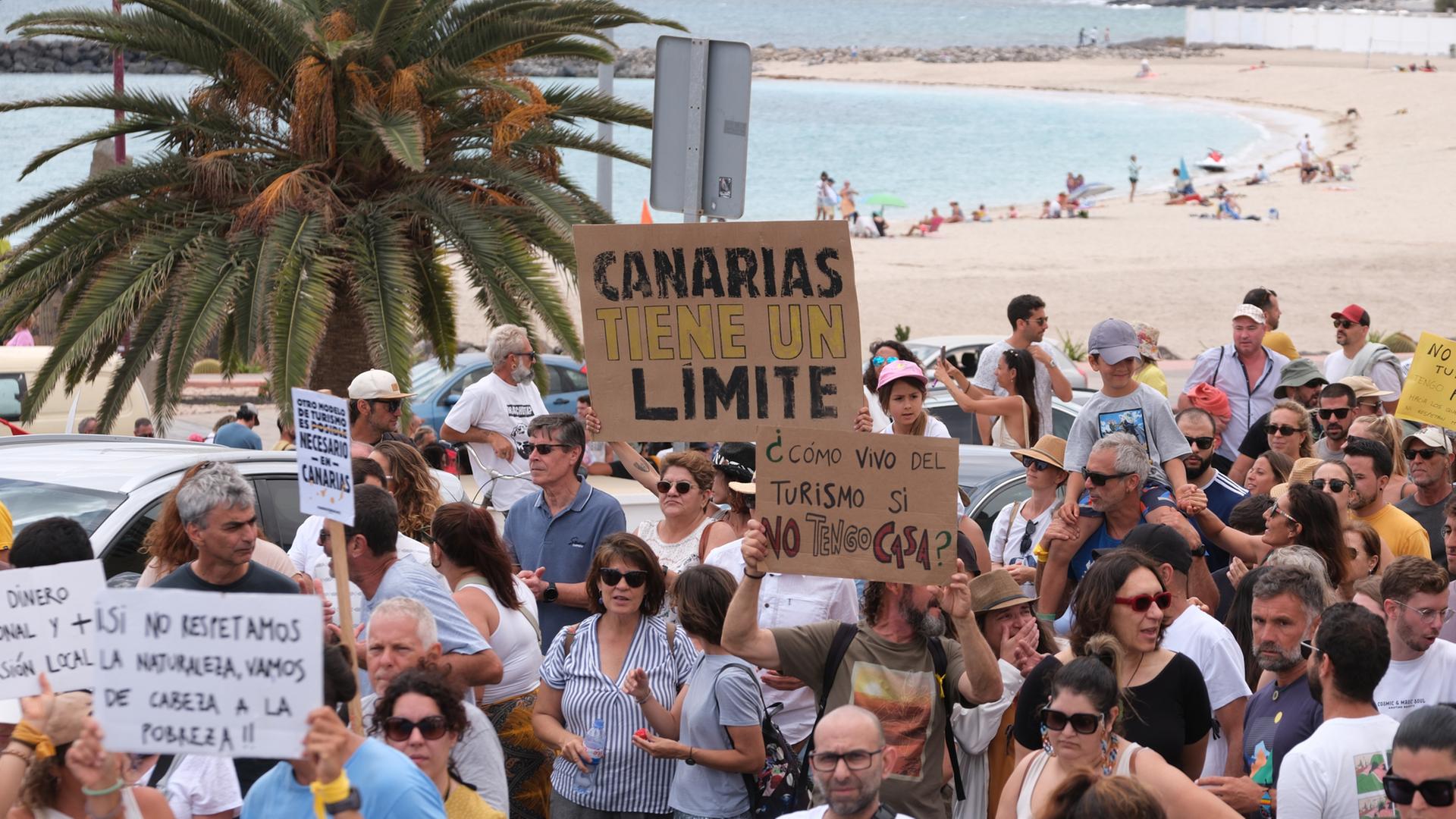 Fuerteventura: Mehrere Personen protestieren mit Plakaten während einer Demonstration gegen das Massentourismusmodell auf den Kanarischen Inseln.