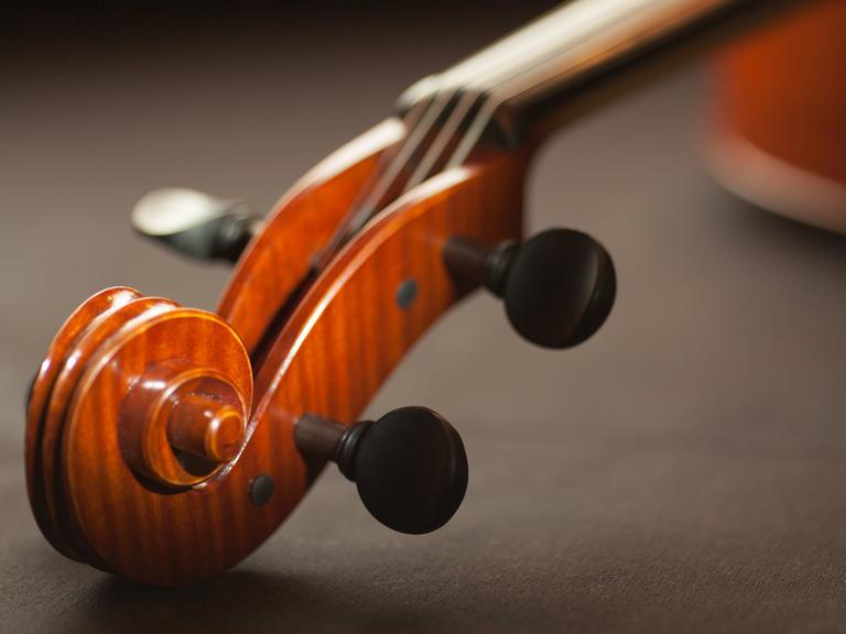 Blick auf die Schnecke einer Violine in Großaufnahme. Sie liegt dabei auf einem Tisch mit dunklem Tuch.