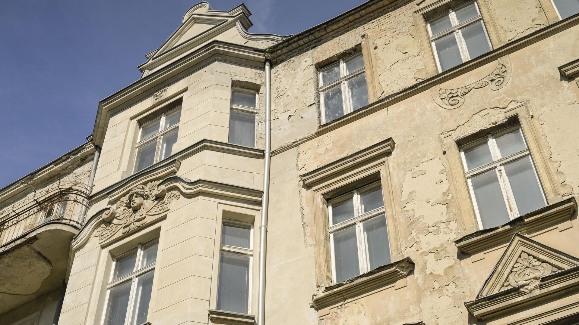 Ausschnitt eines Berliner Mietshauses. Die Fassade und die Fenster sind alt. Es ist erkennbar, dass schon lange nichts mehr an dem Haus gemacht wurde.